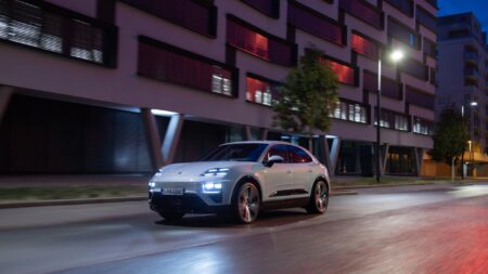 Porsche Macan drives down an empty urban street at night.