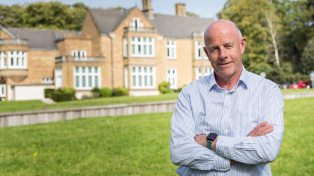 Pete Gillett, founder of Marketpoint Recall, standing in front of a row of houses and a green lawn.