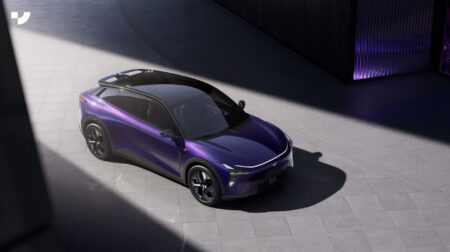 A purple Geely robocar illuminated by a ray of light on a city street