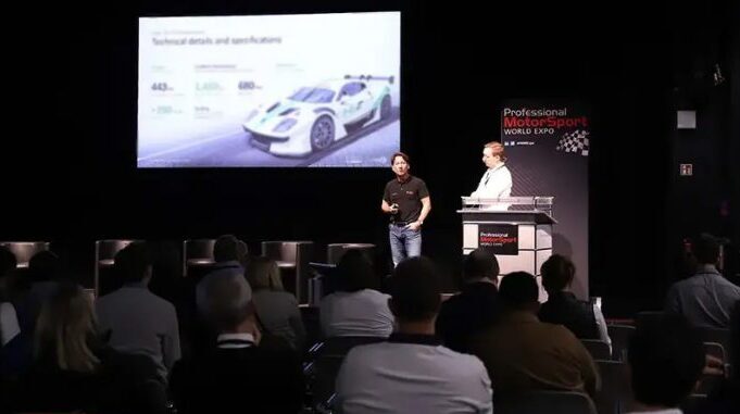 Two men stand on a stage at PMW Expo delivering a lecture.