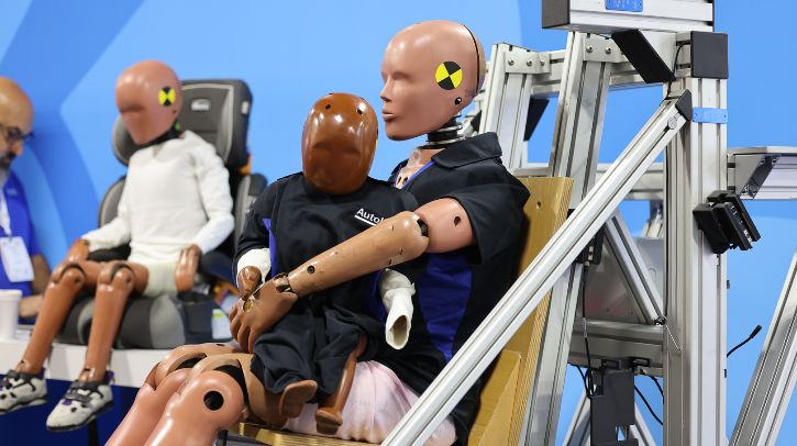 A crash test dummy family is seated inside a vehicle simulator.