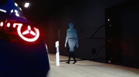 Testing dummy standing on the road in the dark, lit up by an oncoming vehicle.