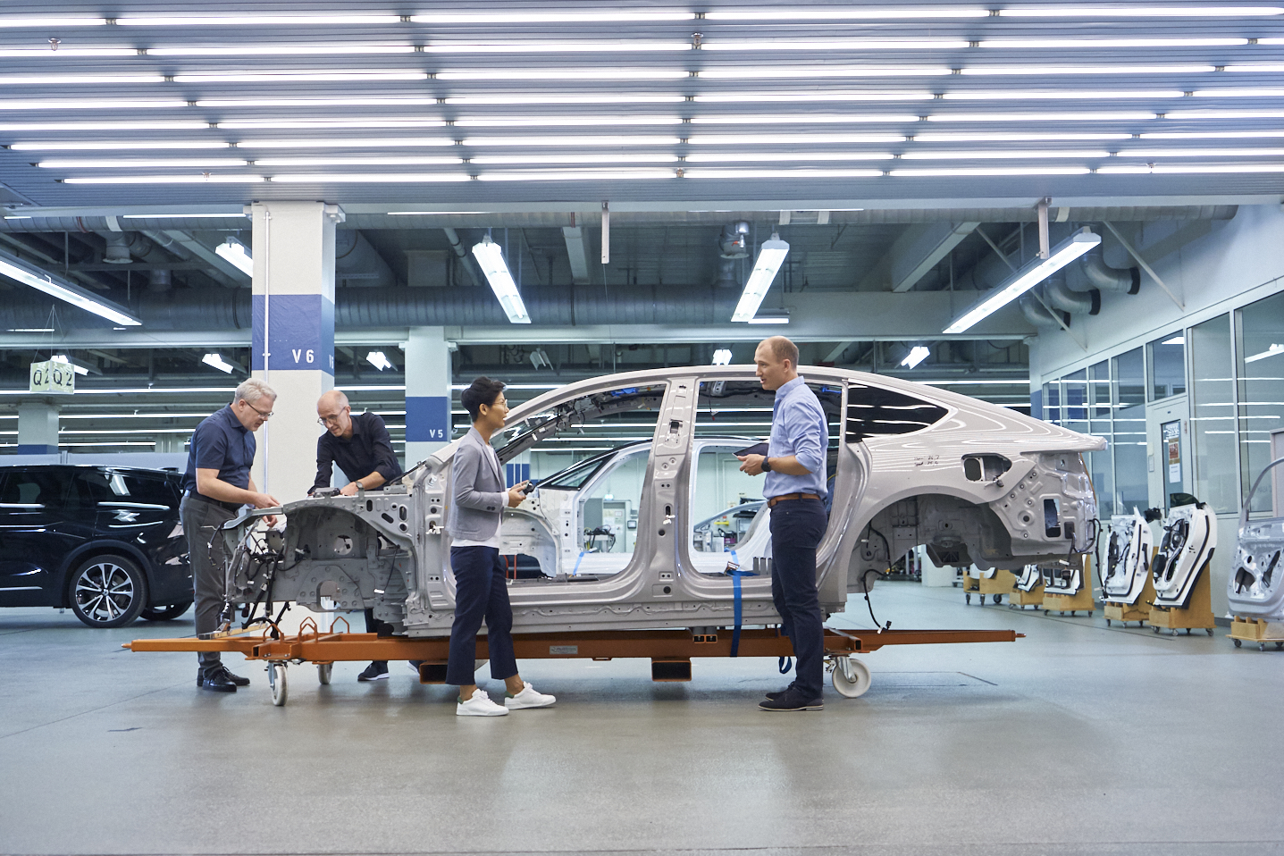 ASAM staff talk in front of a vehicle being constructed in a stark indoor testing laboratory environment