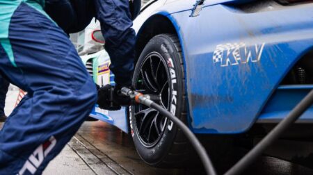 Sumitomo Sensing Core provides real-time tire intelligence in Falken Porsche NLS tests Falken tires with Sensing Core technology on a dark blue race car during an NLS race, with a team member in blue pitstop clothing tightening wheel nuts