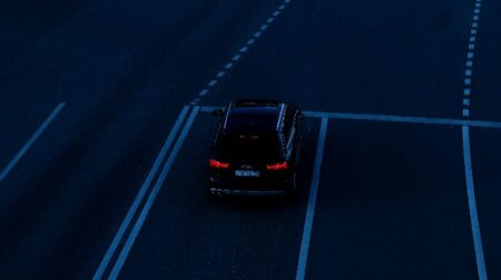 QNX research finds regulatory pressures and development bottlenecks stall UK SDV progress Car is waiting at a traffic light on a dark street.