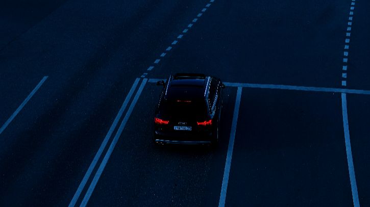 Car is waiting at a traffic light on a dark street.