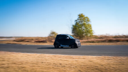 A prototype Smart #2 on track at a desert location. The prototype, which uses the body of the fortwo, is cloaked in camouflage. 