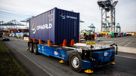 A container is transported by a low-rise, blue autonomous vehicle at DP World's Antwerp Terminal.