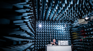 An engineer conducts electromagnetic compatibility testing inside an anechoic chamber, measuring device performance.