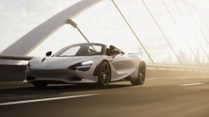 A silver McLaren 750S spider drives along an empty bridge.