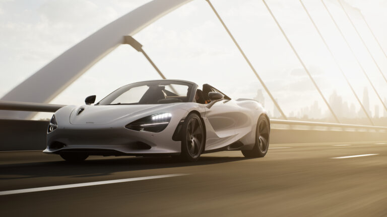 A silver McLaren 750S spider drives along an empty bridge.