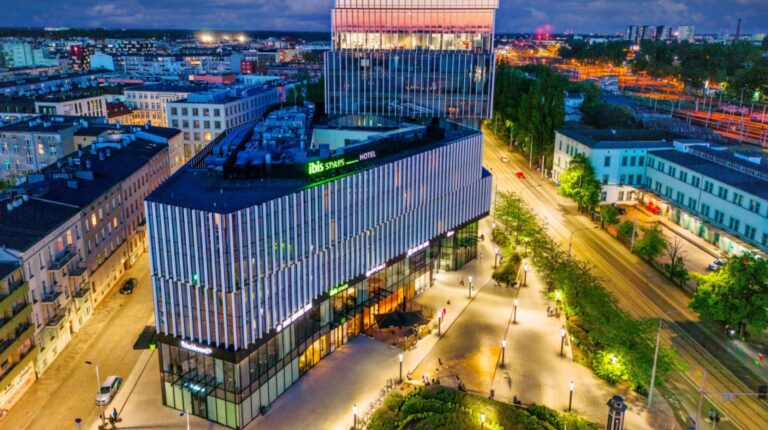 Aerial view of the Toyota Motor Europe Digital Hub in Wrocław, Poland, at night. The building is triangular, and sits on a plot between two major roads.