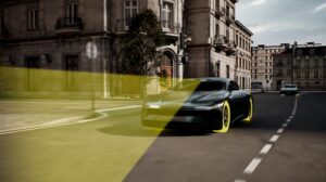 A car drives down an urban street with yellow lines and lights demonstrating its connectivity.