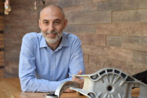 Javier Maruenda, senior vehicle dynamics engineer, Randle Engineering, poses wearing a light blue shirt in front of a brick wall background.