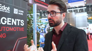 Bruno Finco, co-founder and CTO, MOVEdot, wearing a dark suit and a red shirt. He is interviewed on the show floor.