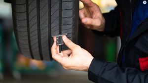A man runs a piece of testing equipment along the side of a tire.