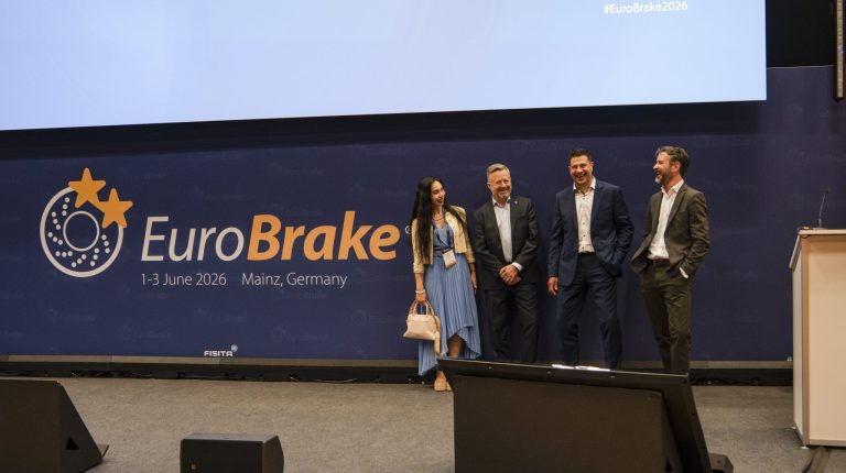 EuroBrake 2026 spotlights emissions, Euro 7 readiness, software-defined braking and integrated system design Representatives of FISITA and Vehicle Tech Week stand on a stage in front of a large screen displaying the EuroBrake 2026 logo.